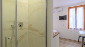 Un bagno moderno con cabina doccia in vetro, un water e un lavandino.