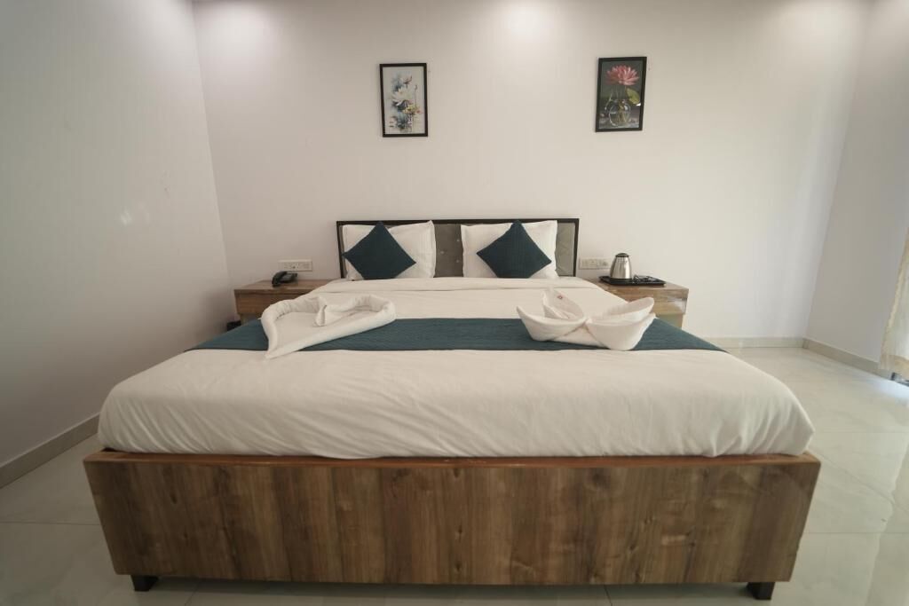 A neatly made bed with a wooden headboard, white bedding, and two pillows. There are two bedside tables with lamps and a small clock.
