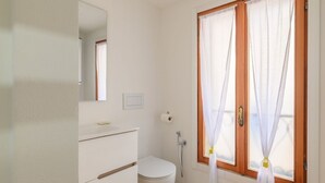 Une salle de bain comprenant des toilettes, un lavabo, un miroir et une douche.