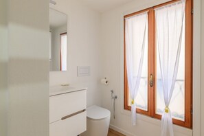 Ein Badezimmer mit Toilette, Waschbecken, Spiegel und Dusche.