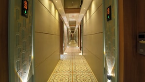 Un long couloir étroit, doté d’un sol et de murs recouverts de carreaux décoratifs, éclairé par des luminaires suspendus au plafond.