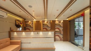Un espace d’accueil au design moderne, comprenant un comptoir de réception, un canapé et un mur décoré d’un motif.