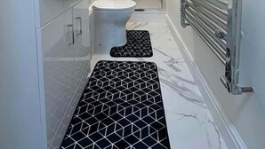 Egy modern fürőszoba fehér mosdókagylóval, WC-vel és zuhanyzóval.