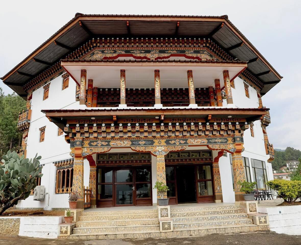 Un bâtiment traditionnel doté de détails architecturaux raffinés, d’un balcon et d’un escalier menant à l’entrée.
