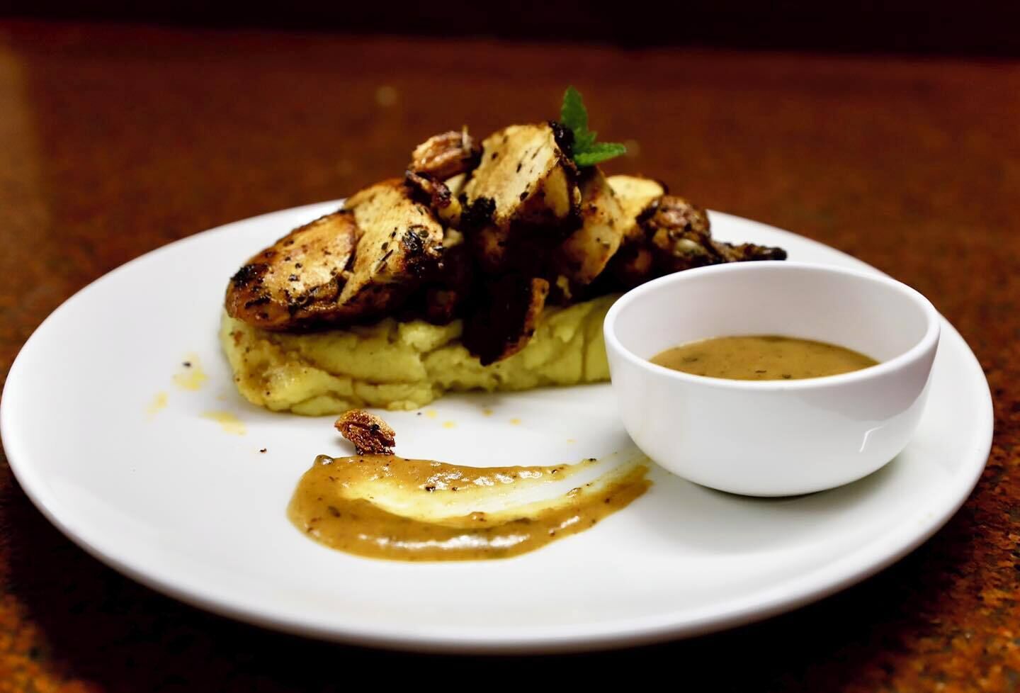Un plato con pechuga de pollo a la plancha, puré de papas y salsa gravy.
