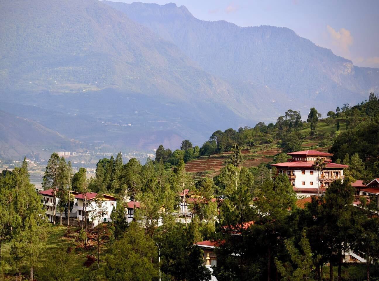 A mountainous landscape with residential buildings, including a prominent white building with a red roof.