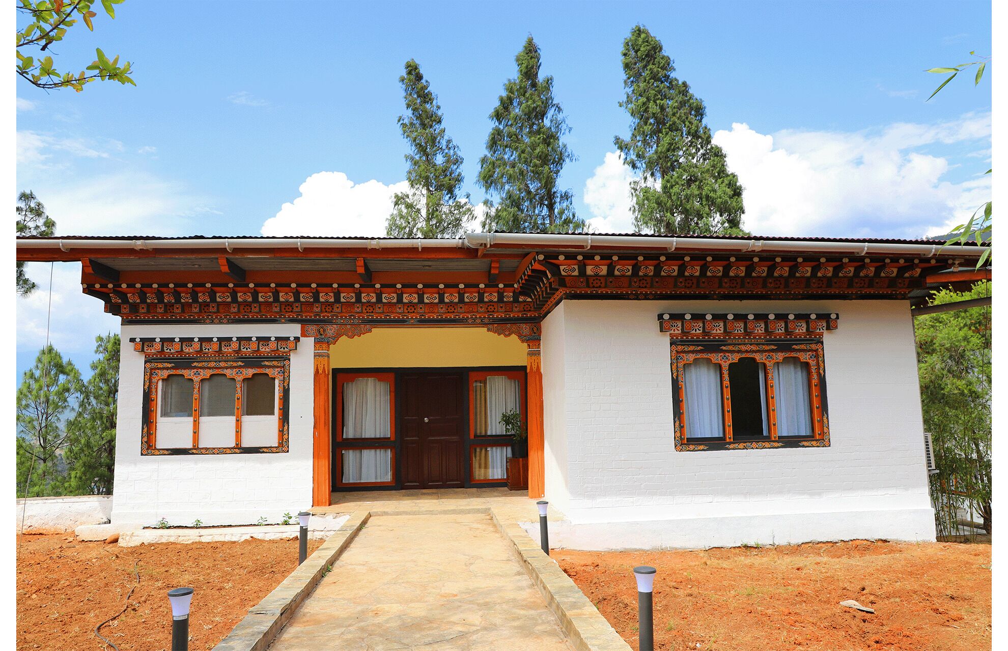 A traditional building with a central entrance, two side windows, and a decorative roof.