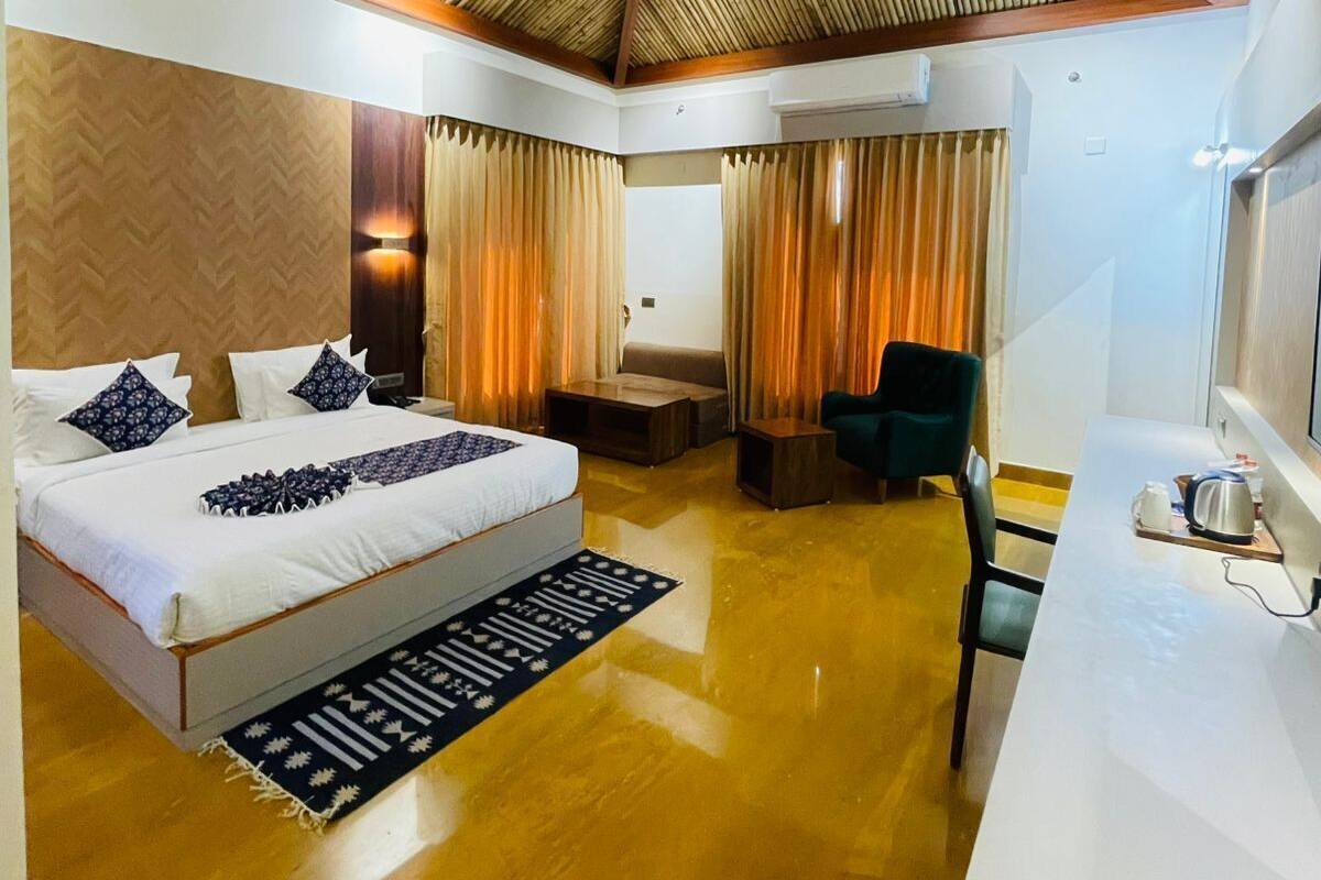 A modern hotel room with a large bed, a desk, a chair, and a ceiling fan.