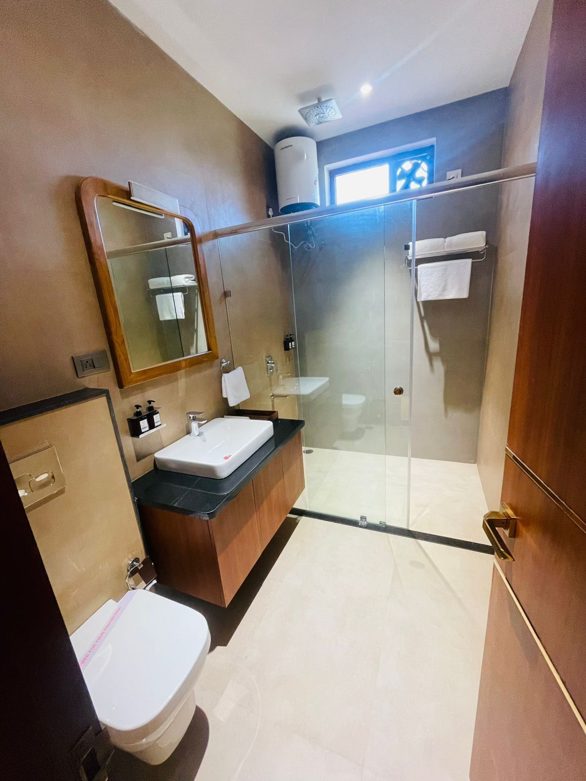 A modern bathroom with a glass-enclosed shower, a sink with a black countertop, and a toilet.