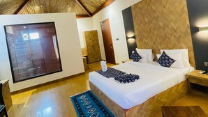 Une chambre avec un grand lit, un plafond en bois, une grande fenêtre et un tapis bleu à motifs.