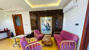 Un salon moderne avec un mur en marbre, un grand tableau représentant un paon et une table basse en bois.
