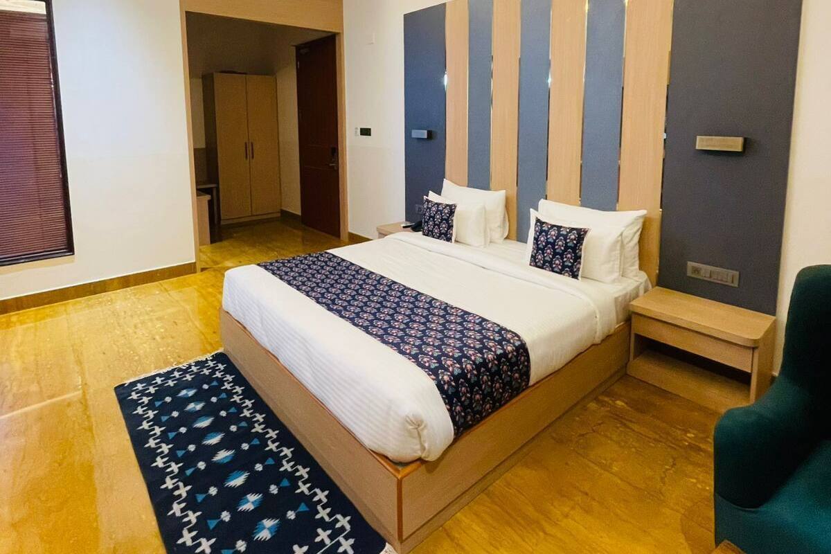 A modern bedroom with a large bed, a ceiling fan, a wooden floor, and a view of a hallway.