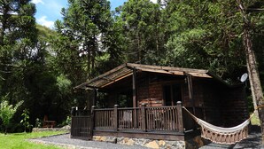 Un chalet rustique doté d’une terrasse en bois et d’un hamac.