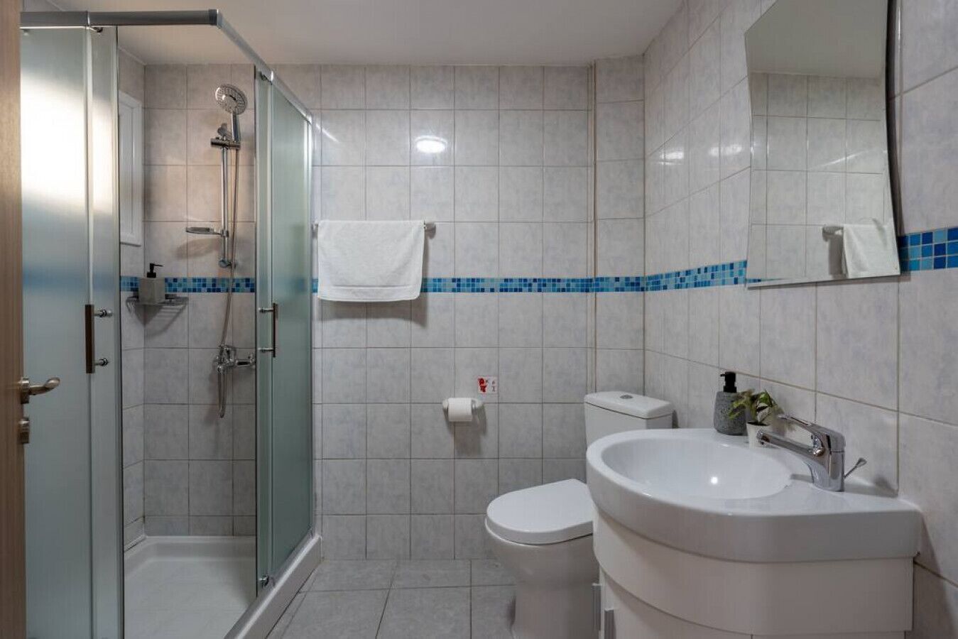 Une salle de bain moderne avec une douche à parois de verre, un lavabo blanc et des toilettes.