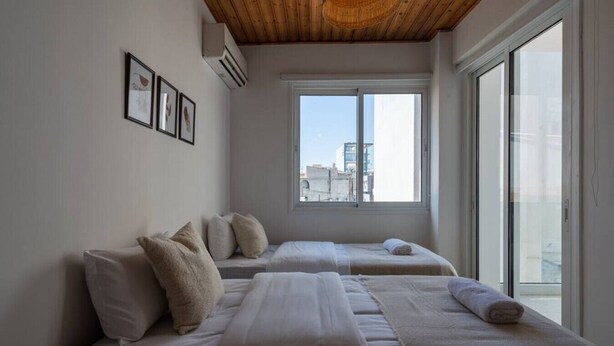 Ein Hotelzimmer mit zwei Betten, einem großen Fenster und einem Deckenventilator.