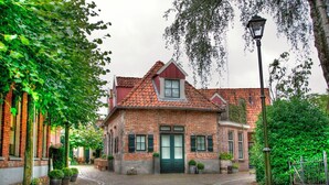 A traditional brick building with a tiled roof, a central entrance with a green door, and a street lamp nearby.