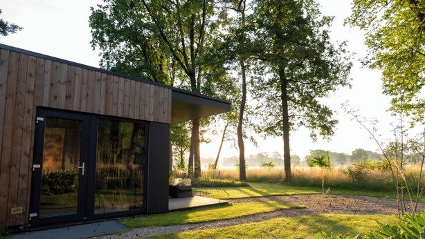 A modern house with a wooden exterior, large glass doors, and a deck.
