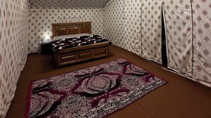 Een tent met een bed, een kroonluchter en gordijnen met een patroon.