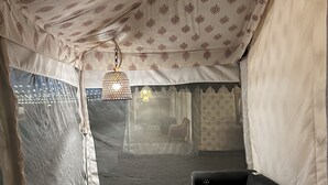 Een tent met een glazen tafel en een zwarte bank.