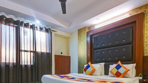 Une chambre d’hôtel avec un grand lit, un ventilateur de plafond et une fenêtre avec des rideaux.