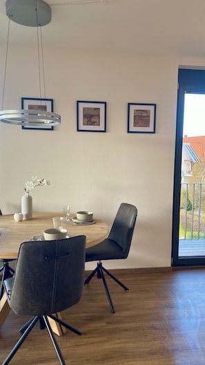 A dining area with a wooden table, two chairs, a vase with flowers, and framed pictures on the wall. - Relaxation at the foot of the Swabian Alb | Cozy apartment in Weilheim / Teck (Weilheim an der Teck)
