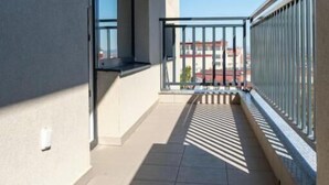 A balcony with a view of buildings, a metal railing, and a tiled floor. - Nest & Rest Brasov - Cozy Apartment (Brasov)