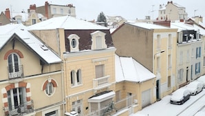 Una strada residenziale con auto e case coperte di neve.