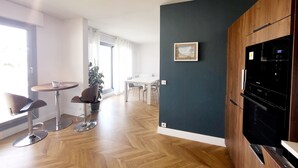 Una cucina moderna con forno integrato e microonde, un'area pranzo con tavolo e sedie, e un'ampia finestra che offre luce naturale.