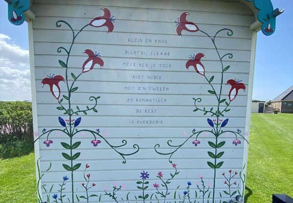 A white building with colorful floral and bird decorations, and text in a foreign language.