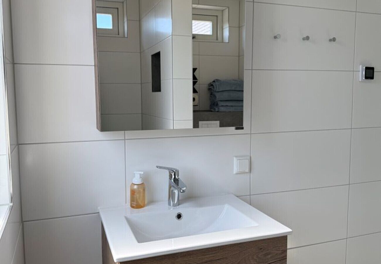 Een badkamer met een witte wastafel, een spiegel en een handdoekhouder.