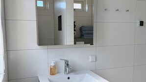 A bathroom with a white sink, a mirror, and a towel rack. - Will's Ranch - Apartment (Den Helder)