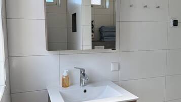 Een badkamer met een witte wastafel, een spiegel en een handdoekhouder.