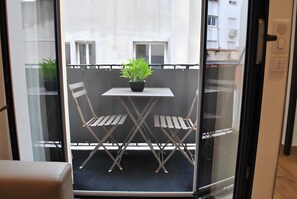 A balcony with a table and chairs, a potted plant, and a view of buildings. - Apartment '2 Pièces Cannes' with Balcony, Wi-Fi and Air Conditioning (Cannes)