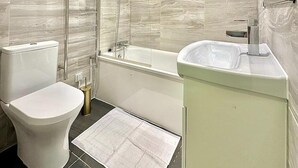 Moderni kylpyhuone, jossa on wc, kylpyamme ja pesuallas.