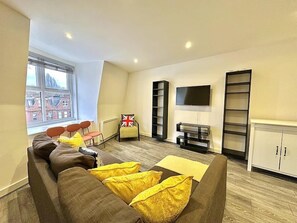A modern living room with a sofa, a TV, and a bookshelf. - Top-floor Apartment by the Station (London)