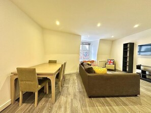 A modern apartment with a dining area, a sofa, and a TV. - Top-floor Apartment by the Station (London)