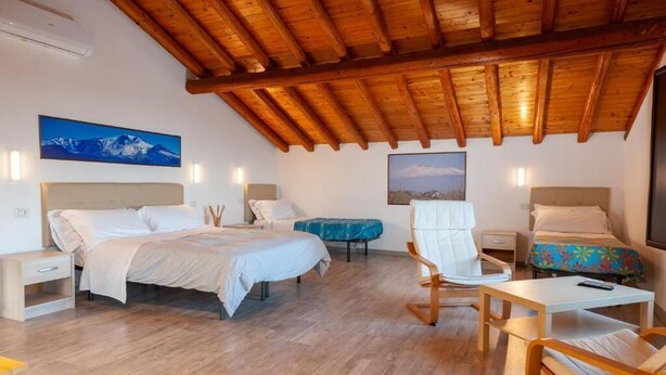Ein Schlafzimmer mit zwei Betten, Holzbalkendecke und einem Bergpanorama an der Wand.
