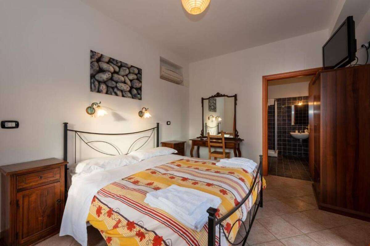 Ein Schlafzimmer mit einem Bett, einem Nachttisch aus Holz, einer Kommode, einem Spiegel und einem Fernseher.