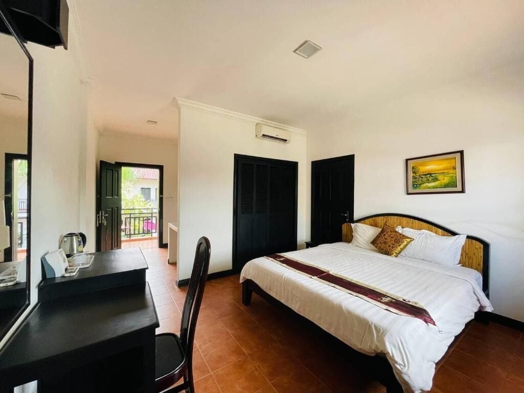 Une chambre d’hôtel avec un lit, un bureau et une chaise. Il y a une fenêtre donnant sur l’extérieur.