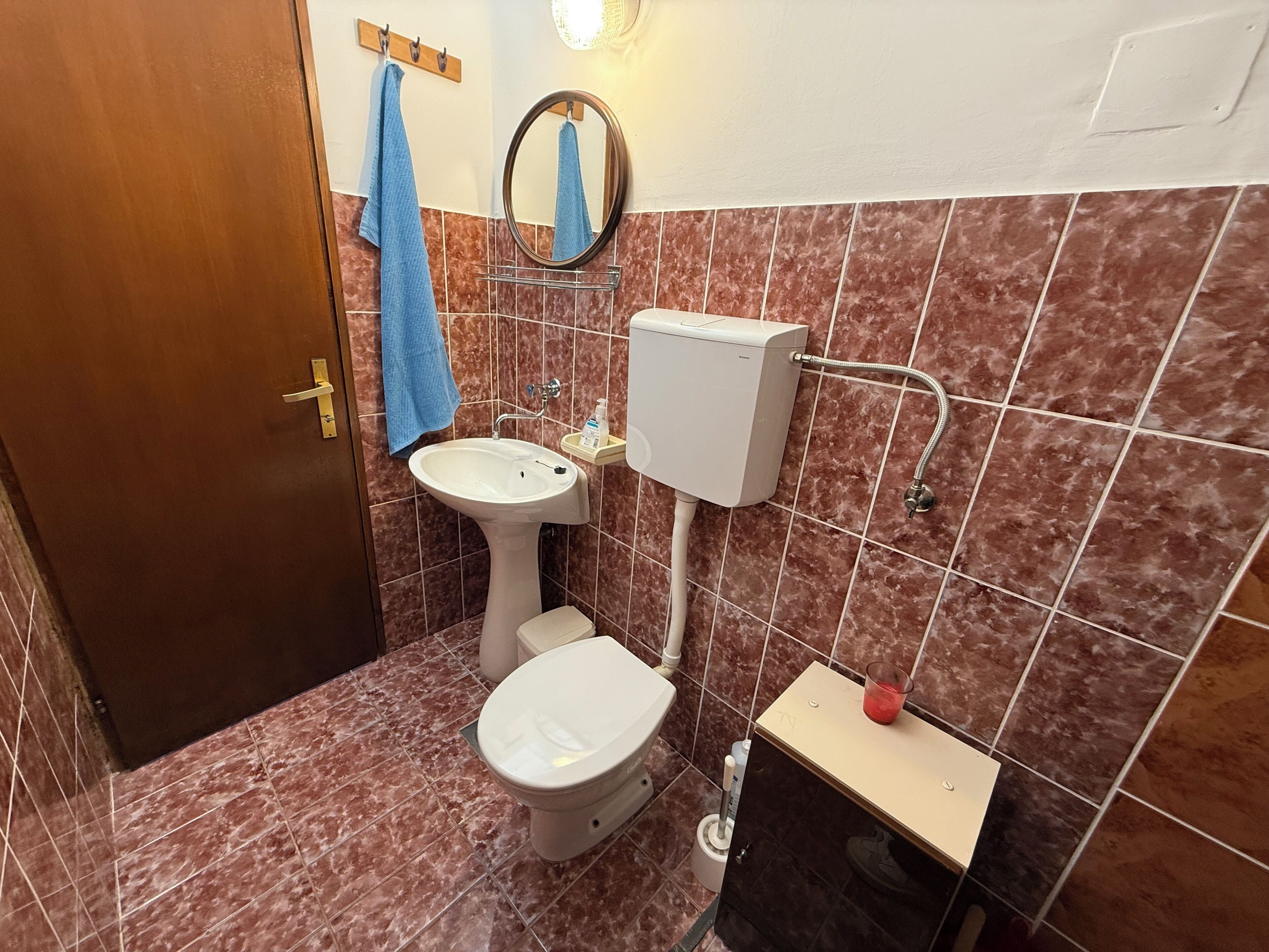 Casa de banho com sanita, lavatório e espelho.