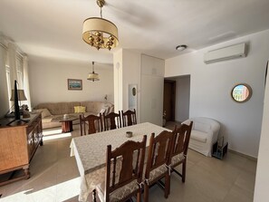 Ein Essbereich mit Tisch und Stühlen, einem Sofa, einer Lampe und einer Deckenleuchte.