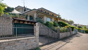 Ein Wohnhaus mit Steinmauer, Metalltor und gepflasterter Auffahrt.