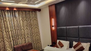 A modern bedroom with a large bed, a sofa, and a ceiling fan. - Hotel Kerni Palace (Katra)