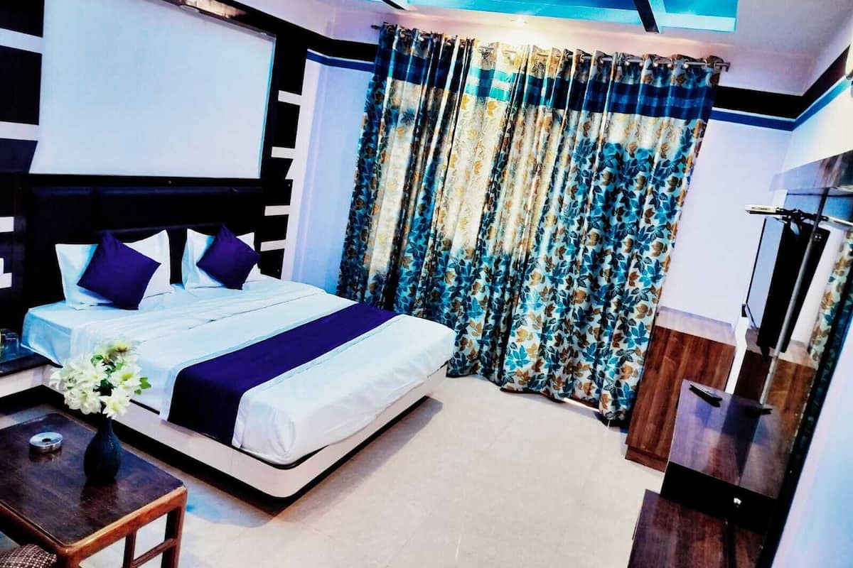 A modern hotel room with a large bed, a ceiling fan, and a view of the outdoors through the window.