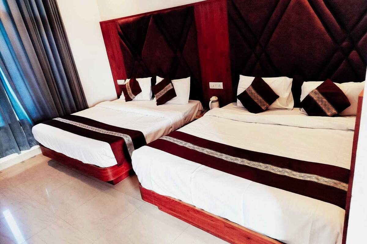 A hotel room with two beds, each with white linens and red headboards.