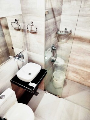 Um banheiro moderno com box de vidro, pia branca e vaso sanitário.