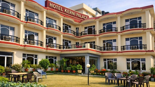 A multi-story hotel with balconies and a central courtyard with seating and plants. - Hotel Kerni Palace (Katra)