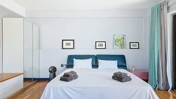 Una habitació d'hotel amb un llit gran, una taula de nit, un mirall i quadres penjats a la paret.