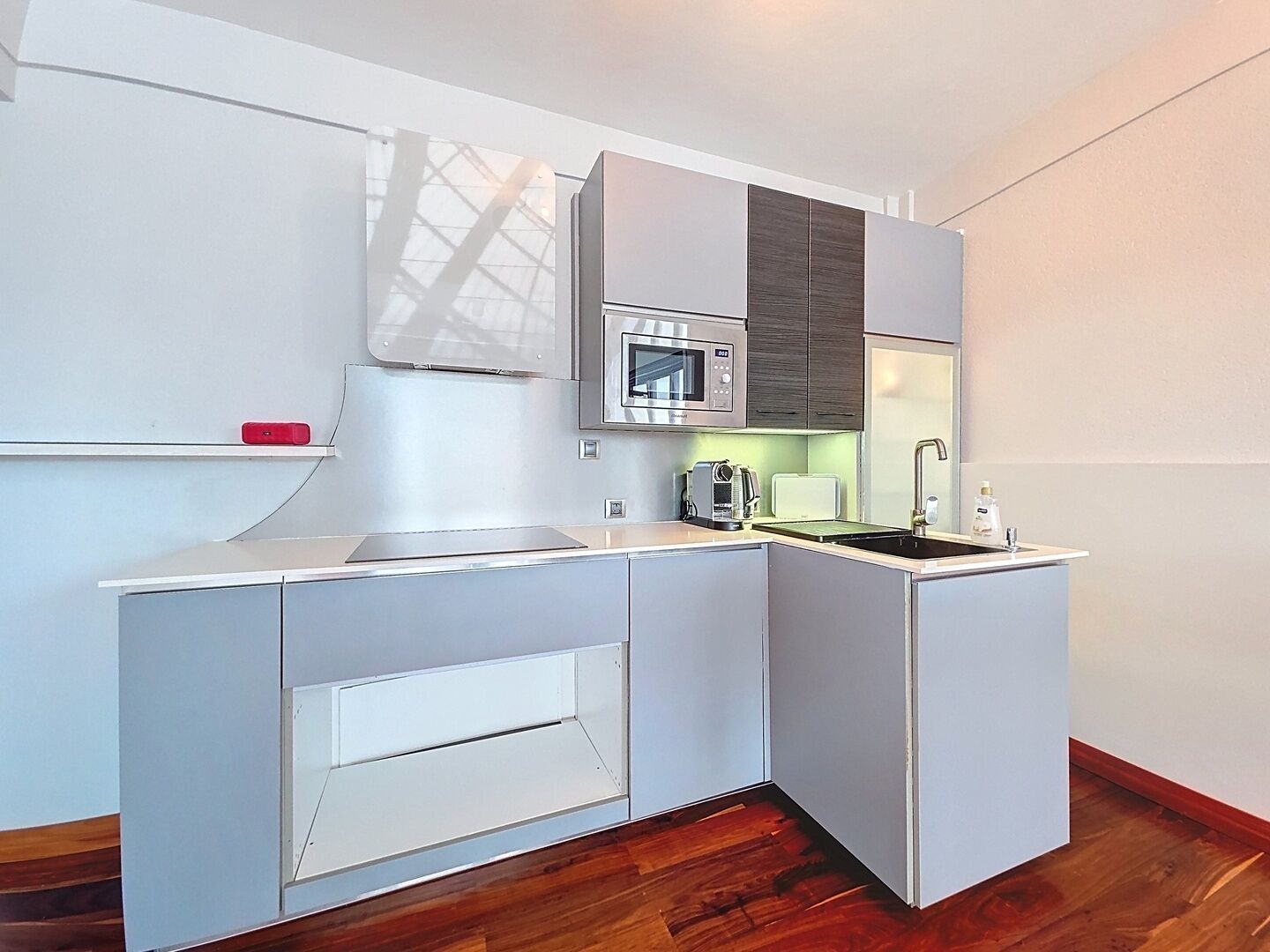 A compact kitchen with a microwave, toaster, and sink.