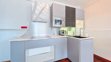 A compact kitchen with a microwave, toaster, and sink.